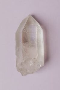 Minimalist photo of a natural clear quartz crystal isolated on a light pastel background.
